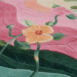 Close-up of a colorful quilted textile featuring embroidered-style flowers in pink, peach, green, and teal with stitched wave-like patterns in the background.