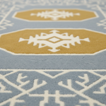 Close-up of a patterned area rug with a light blue base, mustard yellow geometric medallions, and off-white tribal-style motifs.