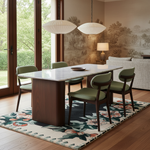 A mid-century modern dining set featuring a rectangular marble-top table with a dark wood base and four matching chairs with olive green seats, styled in a bright dining room on a floral rug.
