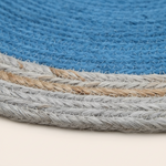 Close-up of a woven round rug showing a blue textured field with braided borders in light gray and natural tan jute.