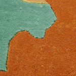Close-up of a textured area rug with an abstract organic pattern in burnt orange and teal green.