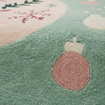 Close-up of a textured area rug with a pastel winter design, featuring a mint green base, a pink ornament, and a pale pink section with embroidered snowflakes.