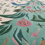 Close-up of a textured rug featuring a whimsical, folk-art style Christmas tree design in mint green, pink, dark green, and cream.
