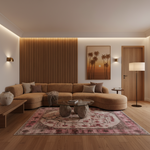 A modern living room featuring a curved beige sectional sofa, a patterned pink and beige area rug, a glass-top coffee table with stone bases, and a warm wood slat accent wall with integrated LED lighting. A framed palm tree sunset print hangs on the wall.